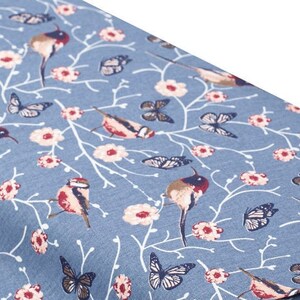 May include: Blue fabric with a repeating pattern of white branches, pink flowers, butterflies, and small birds. The birds are a light brown with red accents.