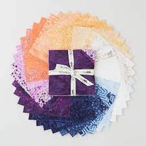 Puede incluir: Una pila de cuadrados de tela dispuestos en abanico circular, con un degradado de colores desde el morado oscuro y azul hasta el naranja claro, amarillo y blanco. La pila central está asegurada con una cinta blanca atada en forma de cruz.