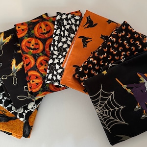Puede incluir: Un conjunto de diez cuadrados de tela con temática de Halloween que presentan varios diseños, incluyendo calabazas, calaveras, brujas y murciélagos. Las telas son negras con acentos naranja y blanco.