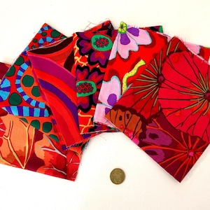 May include: A selection of patterned fabric squares in a fan arrangement. The fabrics feature bold floral and abstract designs in red, orange, purple, and blue hues. A coin is visible at the bottom.
