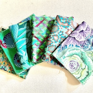May include: A collection of five folded fabric squares featuring diverse patterns. The designs include green floral motifs, a purple and green lattice grid, a teal leopard print, and a large-scale purple and green cabbage leaf illustration.