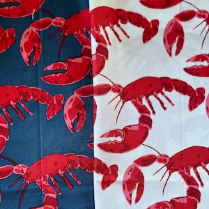 May include: Two fabric swatches with a red lobster pattern. One swatch is dark blue and the other is white.