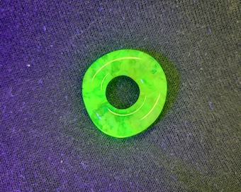 May include: A bright green glass ring with a textured surface. The ring is a simple circle with a hole in the centre.