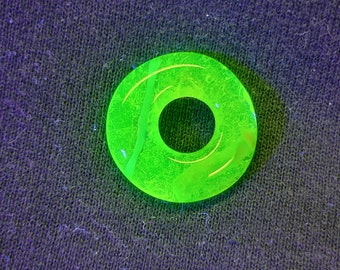 May include: A bright green glass ring with a hole in the centre. The ring has a textured surface and a white line running through it.
