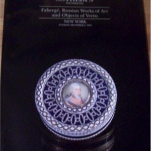 May include: A round, blue and white enamel box with a portrait of a man in a white wig and a blue and gold uniform. The box is decorated with a silver filigree design. Sotheby's is printed on the cover. Fabergé, Russian Works of Art and Objects of Vertu. New York.  Tuesday, December 4, 1990.