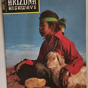 K&ouml;nnte beinhalten: Das Cover der Augustausgabe 1957 des Arizona Highways Magazins. Das Cover zeigt eine Person in einem roten Hemd und einem gr&uuml;nen Stirnband mit einer kleinen Ziege. Der Magazintitel befindet sich in einem gelben Feld.
