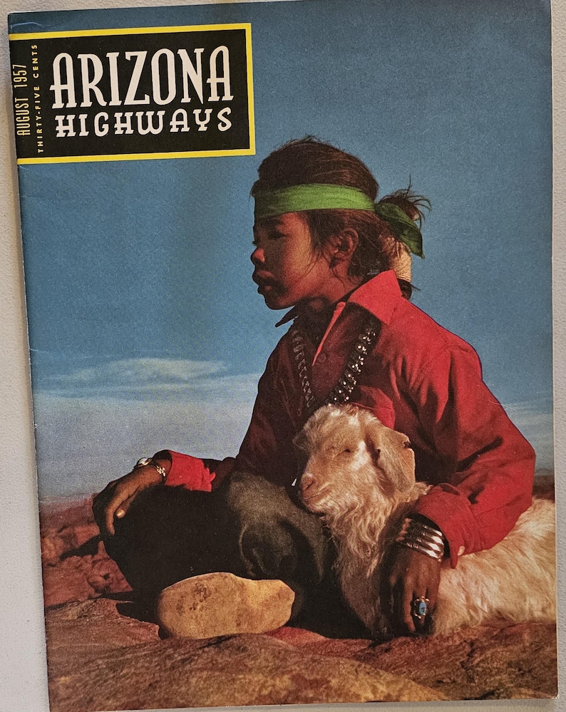 K&ouml;nnte beinhalten: Das Cover der Augustausgabe 1957 des Arizona Highways Magazins. Das Cover zeigt eine Person in einem roten Hemd und einem gr&uuml;nen Stirnband mit einer kleinen Ziege. Der Magazintitel befindet sich in einem gelben Feld.