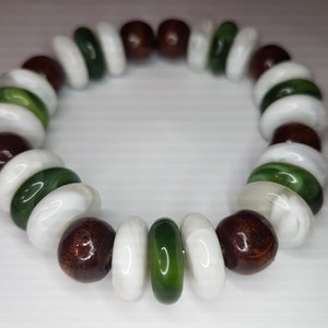 May include: A bracelet made of white, green, and brown beads. The beads are round and have a smooth finish.