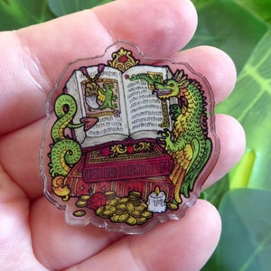 May include: A green dragon with yellow accents is reading a book with gold trim and red pages. The dragon is sitting on a red and gold chest with a candle and a pile of gold coins.