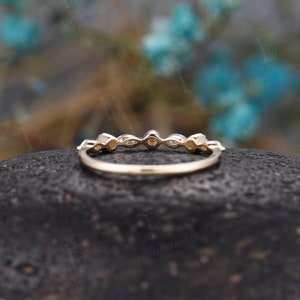 May include: A delicate gold band featuring a row of small, round and oval-shaped gemstones. The band is thin and has a smooth finish.