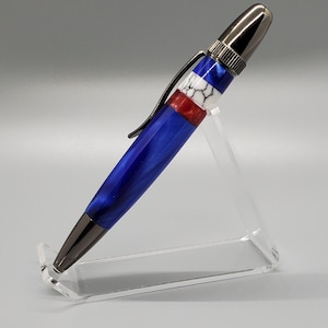 Könnte beinhalten: Ein blauer und weißer Stift mit einem roten Akzent und einer silbernen Kappe. Der Stift steht auf einem durchsichtigen Acrylständer.