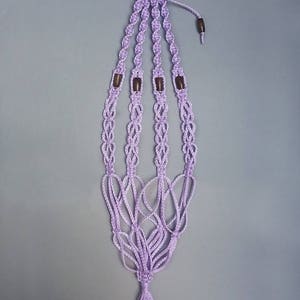 Peut inclure: Un porte-plante en macramé violet avec des perles en bois et un pompon.