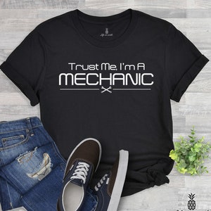 May include: Black t-shirt with white text that reads "Trust Me, I'm A MECHANIC" with a pair of crossed spanners underneath the text.