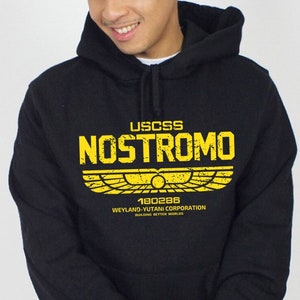 May include: Black hoodie with a yellow graphic print of the text "USCSS Nostromo" with a winged symbol and the text "Weyland-Yutani Corporation Building Better Worlds" underneath.