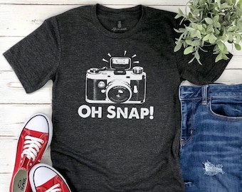 May include: A dark gray t-shirt with a white graphic of a vintage camera and the text "OH SNAP!"