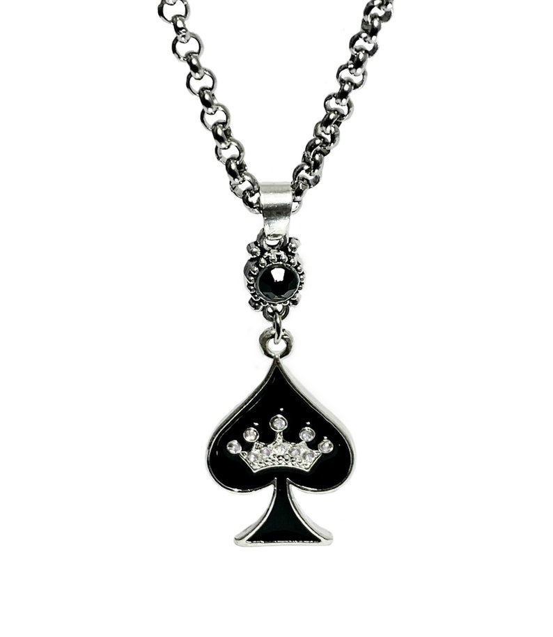May include: A silver necklace with a black spade pendant featuring a crown of white rhinestones. The pendant has a black onyx stone at the top.