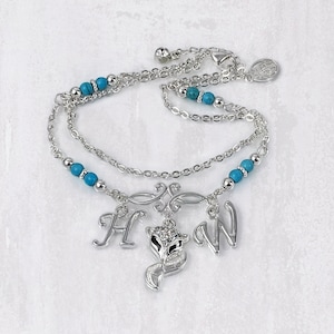 May include: Silver chain anklet with turquoise beads and charms, including a fox, an 'H', and a 'W'.