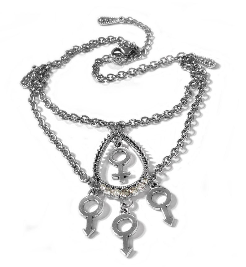 Puede incluir: Un tobillo de cadena de plata con un colgante en forma de l&aacute;grima que presenta un s&iacute;mbolo femenino y diamantes de imitaci&oacute;n. Tres encantos m&aacute;s peque&ntilde;os con s&iacute;mbolos masculinos cuelgan del colgante.