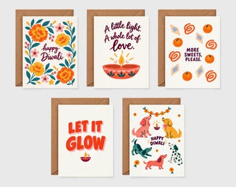May include: A set of five greeting cards with brown envelopes. Designs include orange marigolds with 'happy Diwali', a diya lamp with 'A little light. A whole lot of love.', sweets with 'MORE SWEETS, PLEASE.', 'LET IT GLOW' with a diya, and dogs with 'HAPPY DIWALI'.