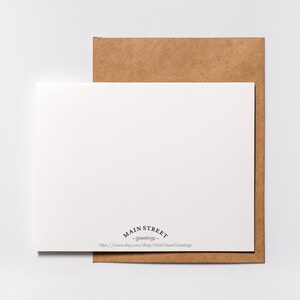 May include: A blank white card with a brown envelope behind it. The card has the text "Main Street - greetings -" and a website address printed on the bottom.