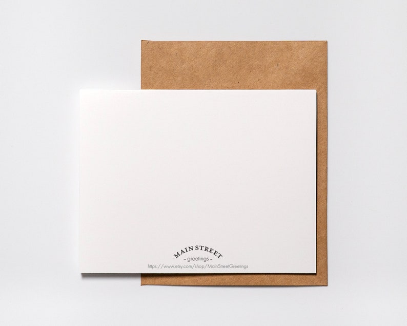 May include: A blank white card with a brown envelope behind it. The card has the text "Main Street - greetings -" and a website address printed on the bottom.