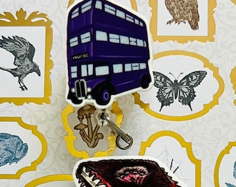May include: Two Harry Potter themed retractable badge reels. The first reel features a purple double-decker bus with the text "Knight Bus". The second reel features a red book with a monstrous face and teeth.