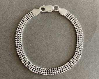 Puede incluir: Un brazalete de cadena de plata con un diseño delicado y multicapa. El brazalete tiene un cierre de langosta.