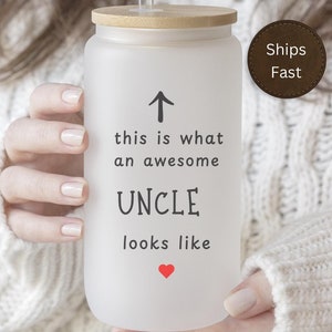 May include: White frosted glass tumbler with a bamboo lid and a straw. The tumbler has a black arrow pointing up and the text "this is what an awesome UNCLE looks like" with a small red heart.