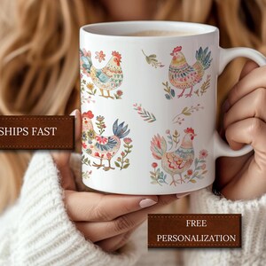 May include: White ceramic mug with a colorful rooster design. The rooster is depicted in a watercolor style with floral accents. The mug has a handle and is suitable for hot beverages.