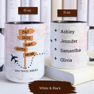May include: Two white ceramic mugs with black handles. One mug features a map with a plane and a signpost with the words "Italy", "Greece", "France", "Austria", and "England". The other mug has a map with the names "Ashley", "Jennifer", "Samantha", and "Olivia". Both mugs have the text "2025 Travel Diaries".