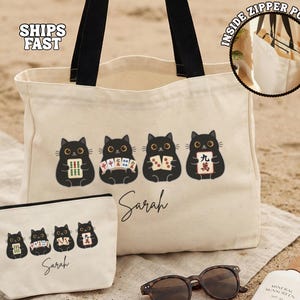 May include: A cream-colored canvas tote bag and matching zippered pouch, both featuring a graphic of four black cats holding mahjong tiles and the name Sarah in black script. The tote has black handles and an interior zippered pocket.