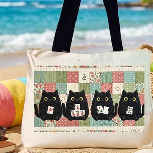 May include: A cream-colored canvas tote bag with black shoulder straps. The front features a printed patchwork design in shades of green, pink, and white, displaying four black cats holding mahjong tiles with various Chinese characters.
