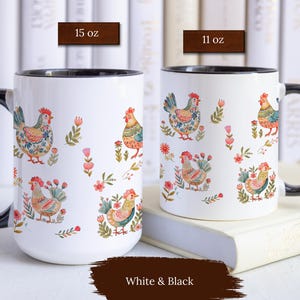 May include: Two white ceramic mugs with black rims and handles. Both mugs feature a colorful pattern of stylized chickens and flowers. The mug on the left is 15 oz and the mug on the right is 11 oz.