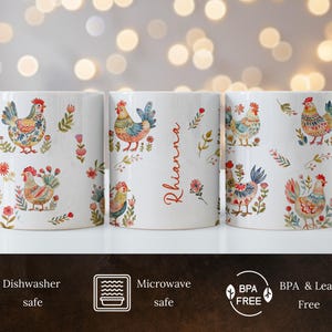 May include: Three white ceramic mugs with a colorful rooster pattern and floral accents. The mug in the center has the name "Rhianna" written on it. The mugs are dishwasher and microwave safe and BPA and lead free.