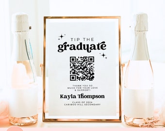 May include: A gold-framed sign with a white background and black text that reads "Tip the graduate". The sign also includes a QR code and the text "Thank you so much for your love & support! Kayla Thompson Class of 2024 Cariboo Hill Secondary".