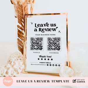 May include: A white sign with black text that says "Leave us a Review" with a QR code for Google and Facebook reviews. The sign also says "Thank You!" and has a five-star rating. The sign is in a gold frame.
