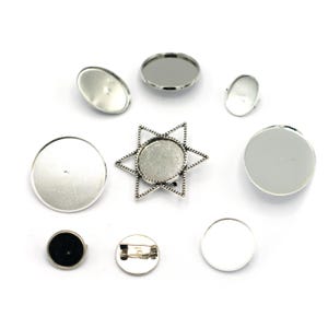 Op de afbeelding: Assortiment van zilverkleurige metalen blanco ronde en stervormige hangerbakjes voor het maken van sieraden. De bakjes zijn perfect om hars, glas of andere materialen aan toe te voegen om eigengemaakte sieraden te creëren.