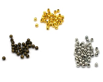 May include: Three piles of round metal beads in different colors: gold, bronze, and silver. The beads are small and uniform in size.