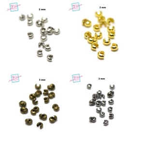 May include: Four piles of 3 mm crimp end beads in silver, gold, bronze, and nickel. The beads are small and round with a small opening on one side.
