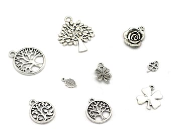 Könnte beinhalten: Eine Sammlung silberfarbener Metall-Anhänger mit verschiedenen Designs, die von der Natur inspiriert sind, darunter Bäume, Blätter, Blumen und vierblättrige Kleeblätter.