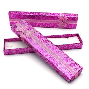 Op de afbeelding: Twee roze geschenkdozen met een bloemenpatroon en een roze lint. De dozen zijn gemaakt van karton en hebben een satijnen afwerking.