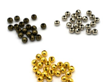 May include: Three piles of round metal beads. One pile is gold, one is silver, and one is bronze.