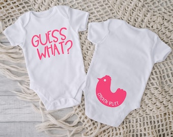 May include: Two white baby onesies. The onesie on the left says "Guess What?" in pink lettering. The onesie on the right has a pink chicken silhouette with the words "Chicken Butt" underneath.