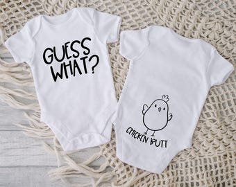 May include: Two white baby onesies. One onesie has the text "GUESS WHAT?" printed in black. The other onesie has a black and white illustration of a chick with the text "CHICKEN BUTT" printed below.