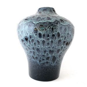 May include: A decorative ceramic vase with a unique speckled pattern. The vase features a dark blue and teal color scheme with a textured surface. The vase has a wide body and a narrow neck, suitable for floral arrangements.