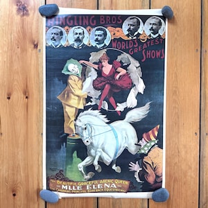 May include: Vintage circus poster featuring the Ringling Bros. World's Greatest Shows. The poster showcases a white horse, a clown, and a woman in a red dress. The text reads "MLLE ELENA" and "The Charming Principal Bareback Equestrienne."