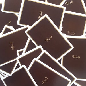 May include: A stack of brown cards with gold lettering that reads "Walt" on each card.