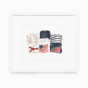 May include: Watercolor painting of folded shirts with patriotic themes. One shirt features a red lobster, while others display the American flag and blue and white stripes. The artwork is framed in a white border.