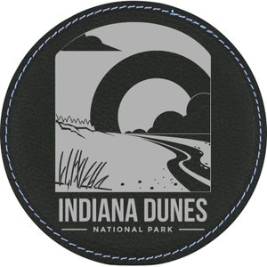 May include: A black leather coaster with a gray image of a beach scene and the text "Indiana Dunes National Park".