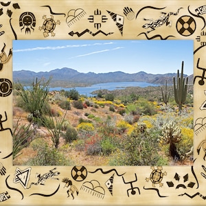 May include: A framed photograph of a desert landscape with a lake in the distance. The frame is decorated with Native American-inspired artwork, including handprints, animals, and geometric patterns.